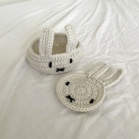 two crocheted bunny baskets on a bed