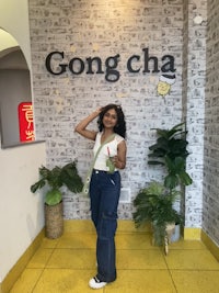 a woman standing in front of a sign that says gong cha