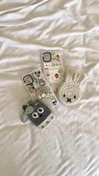 two crocheted phone cases laying on a bed
