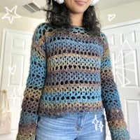 a woman wearing a crocheted sweater and earphones